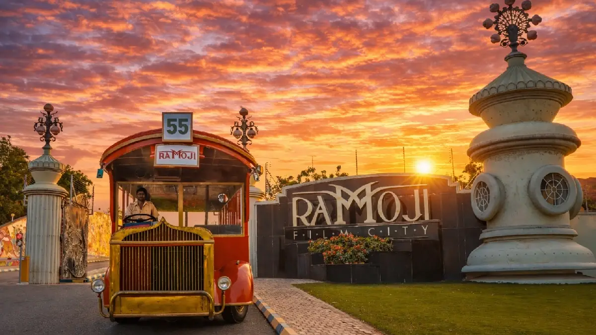 The main entrance of Ramoji Film City at sunset, with one of the film city's vintage tour buses waiting at the gate